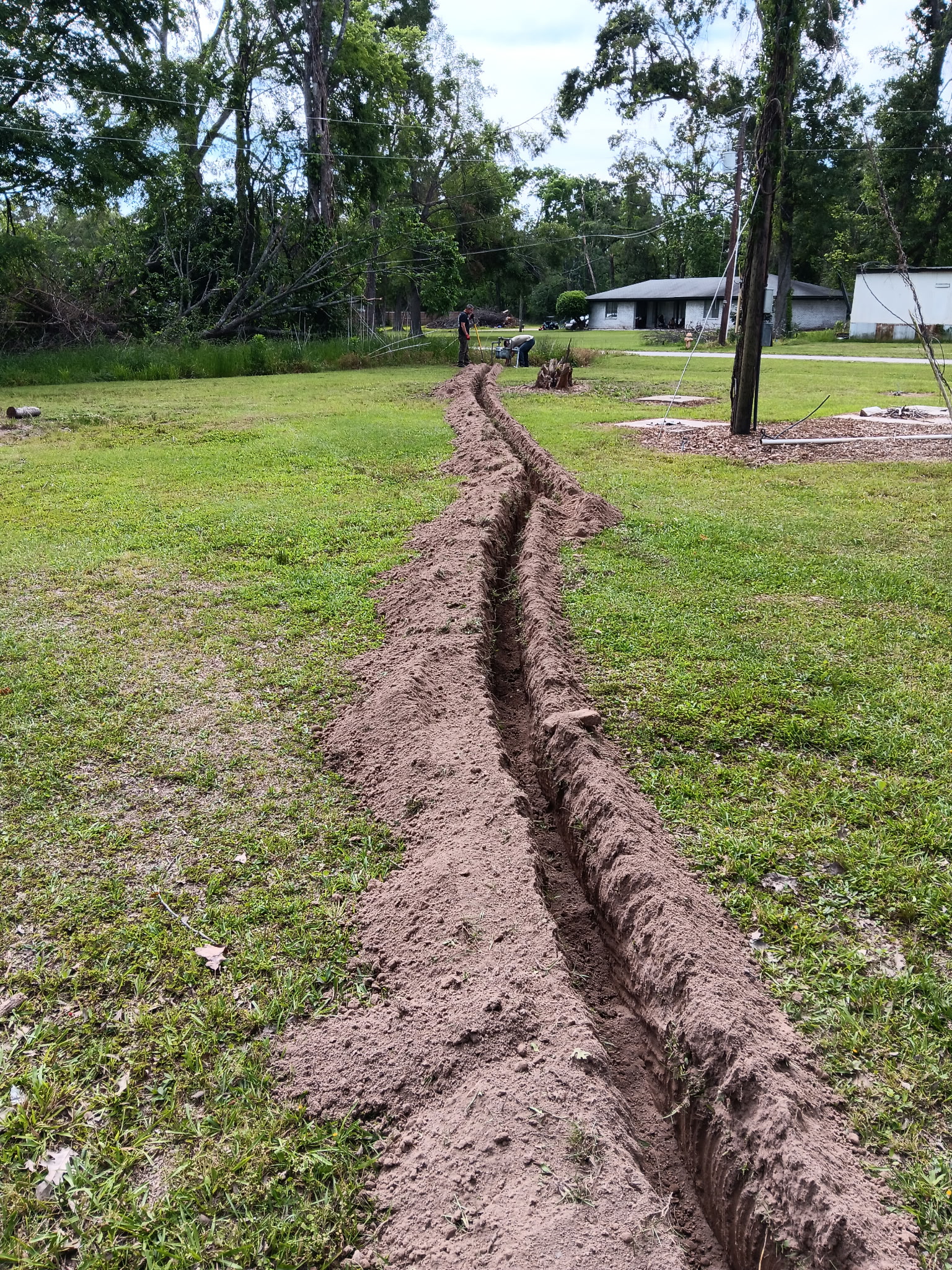 Full-length trench across lawn with crew working, McKinney, TX