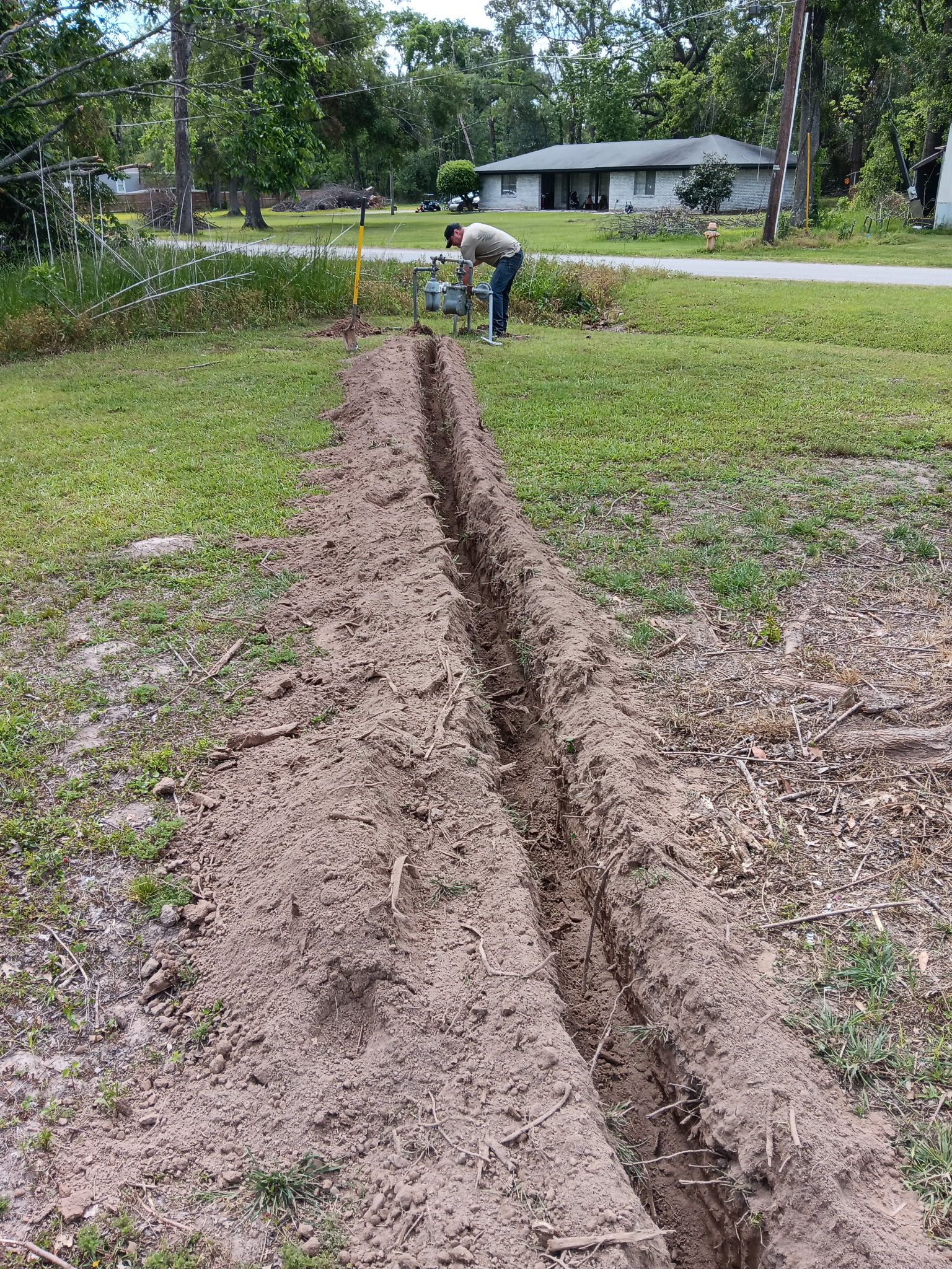 Crew member connecting gas meter at trench end, McKinney, TX