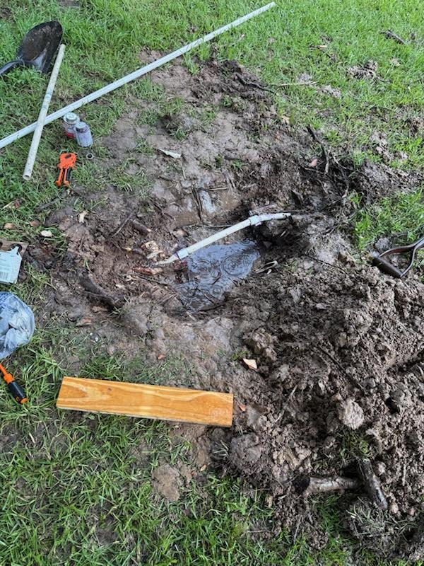 Active excavation with broken pipe exposed and standing water, near Dallas, TX